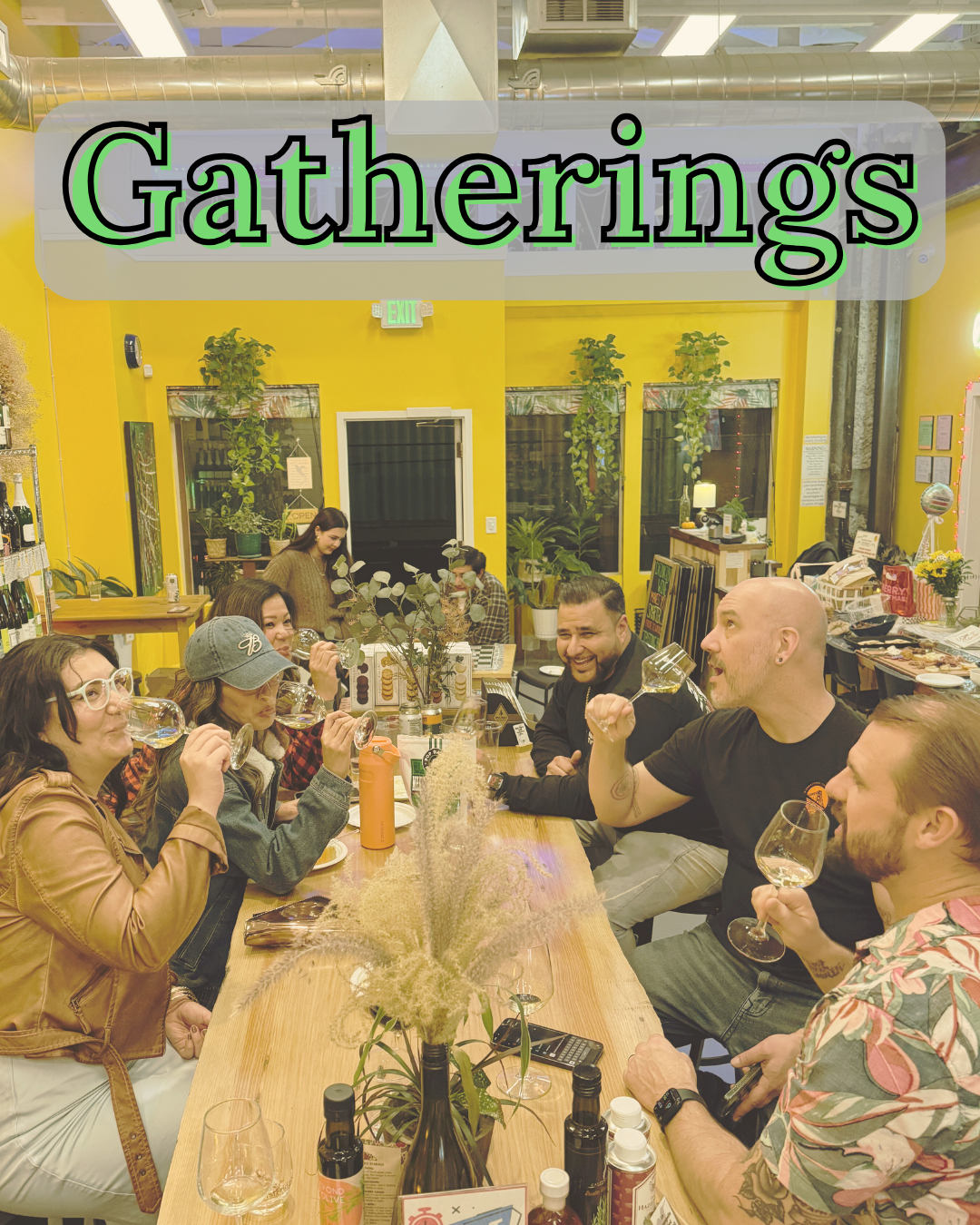 People gathered around a table in a room with yellow walls, enjoying drinks and food.