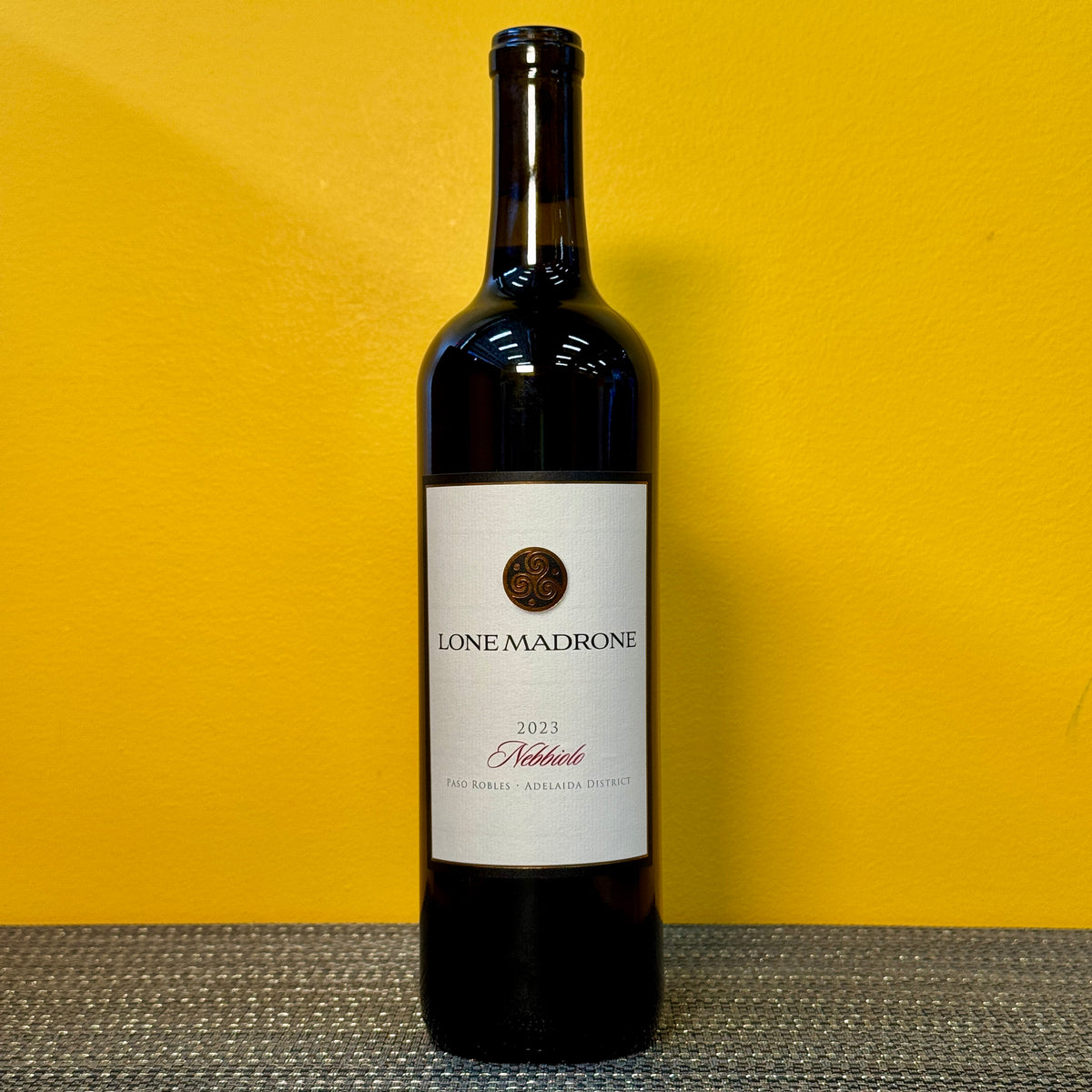 Wine bottle labeled 'Lone Madrone Nebbiolo' on a yellow background