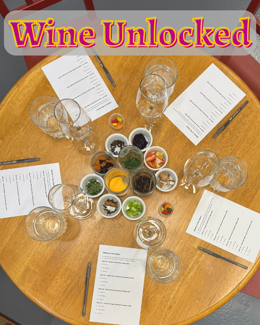 Wine tasting setup with glasses, notes, and food on a wooden table, branded 'Wine Unlocked'.